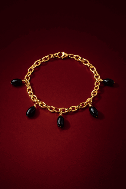 Gold chain bracelet with black beads on a red background, Agatha Bracelet by VINTARAS.