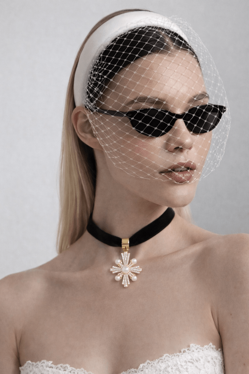 Cross-shaped pendant featuring pearls and small crystals on a black velvet necklace