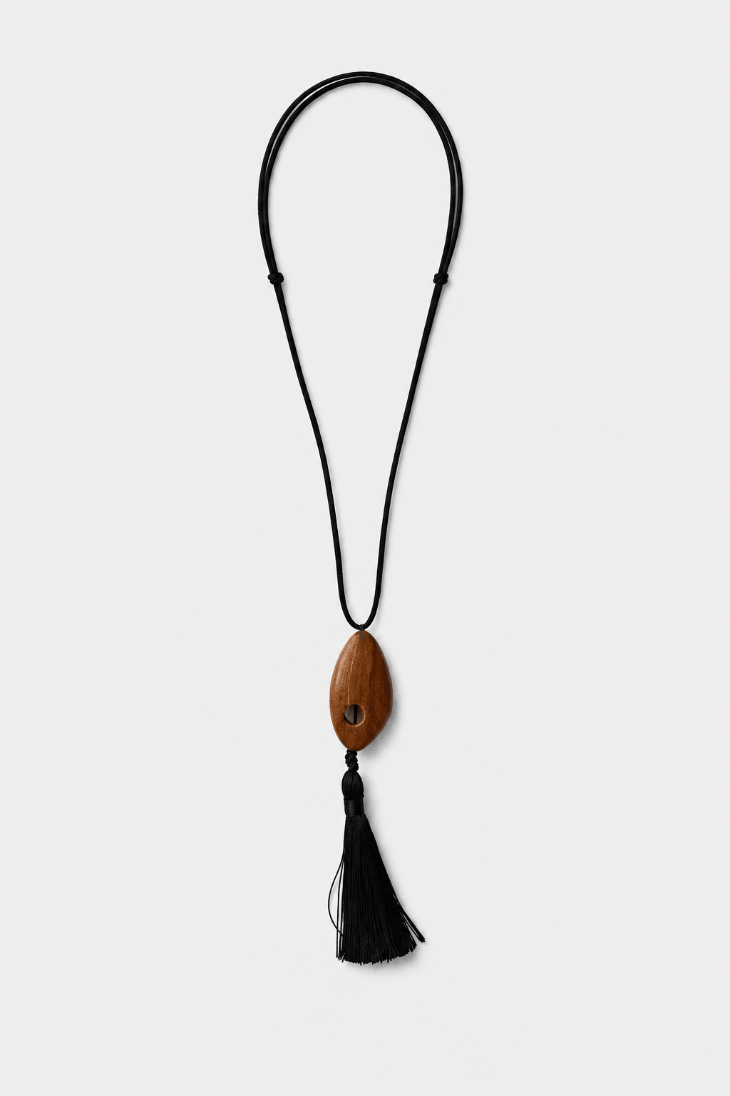 Necklace with a wooden pendant and black tassel on a white background
