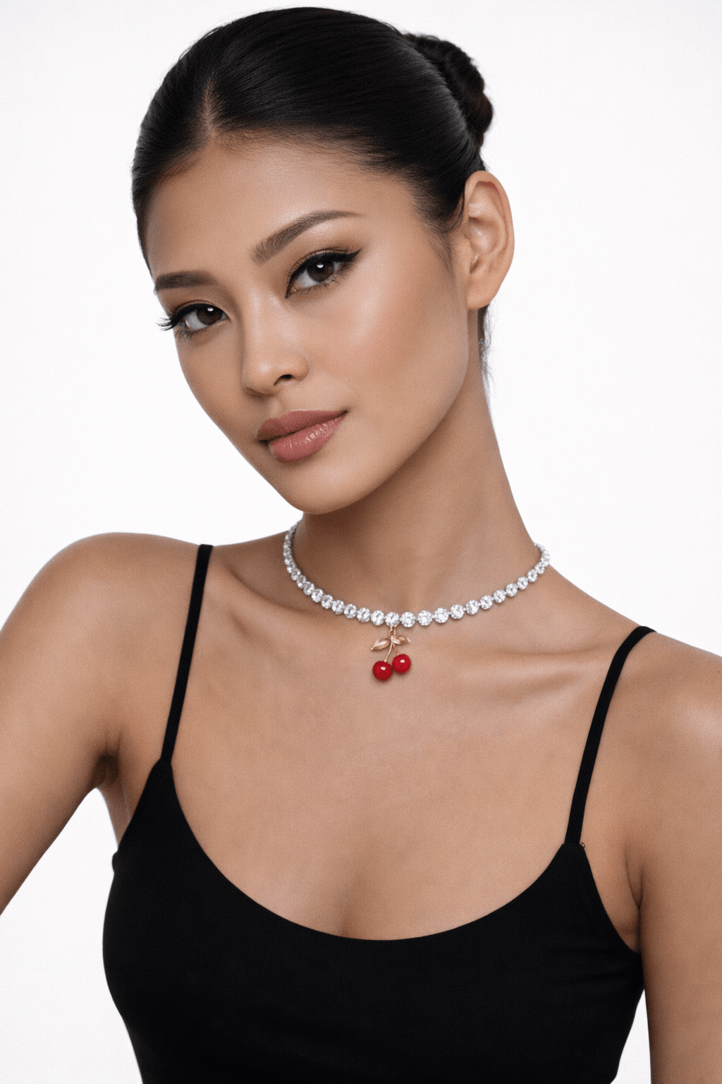 Woman wearing a black top and a necklace with red cherry pendants on a white background