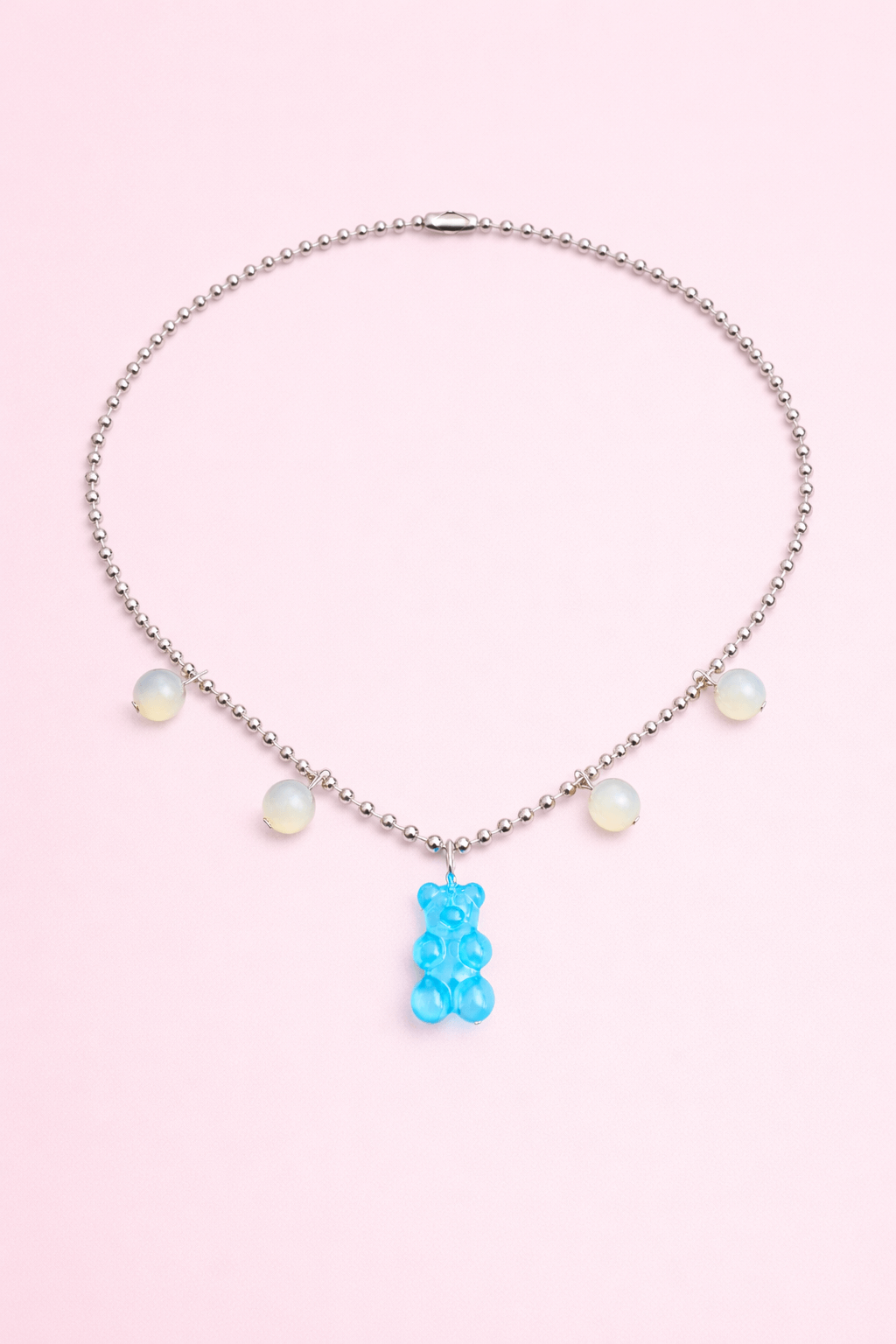 Dolce Bear Necklace with a blue gummy bear pendant on a pink background