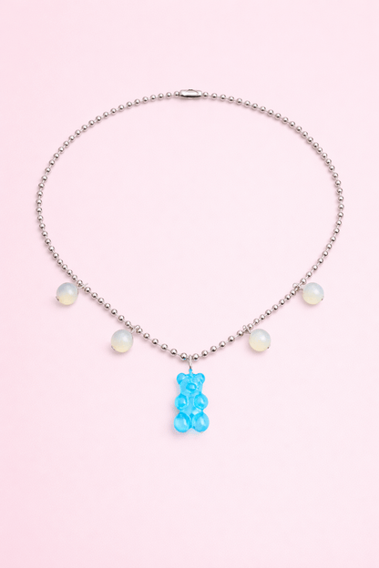 Dolce Bear Necklace with a blue gummy bear pendant on a pink background