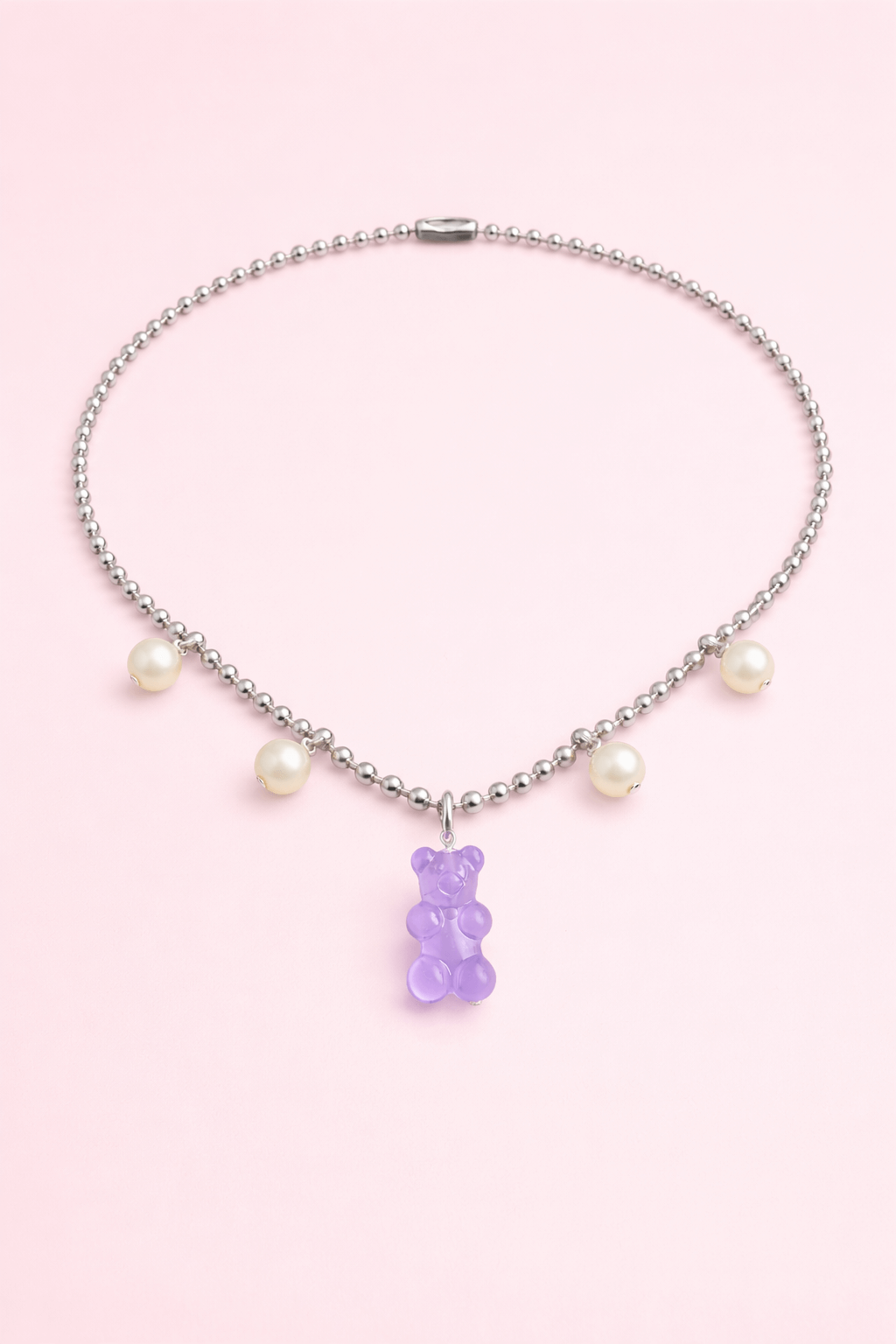 Dolce Bear Necklace with a purple gummy bear charm and pearl beads on a pink background