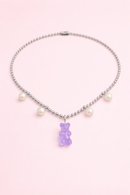 Dolce Bear Necklace with a purple gummy bear charm and pearl beads on a pink background