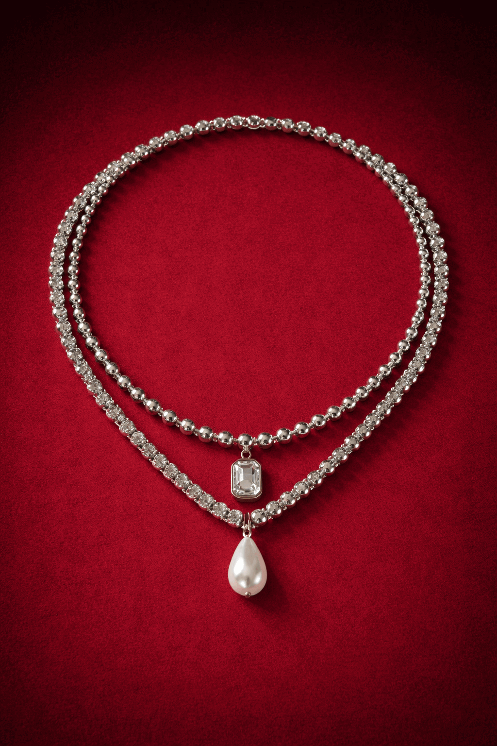 Necklaces layered,  including a zirconia tennis necklace with a pearl pendant and ball chain necklace with zirconia pendant on a red background, Josephine Necklace Set by Vintaras.