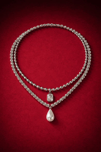 Necklaces layered,  including a zirconia tennis necklace with a pearl pendant and ball chain necklace with zirconia pendant on a red background, Josephine Necklace Set by Vintaras.