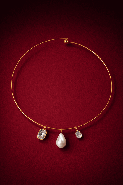 Gold necklace with three pendant stones on a red background, Trio Cuff Necklace by VINTARAS.
