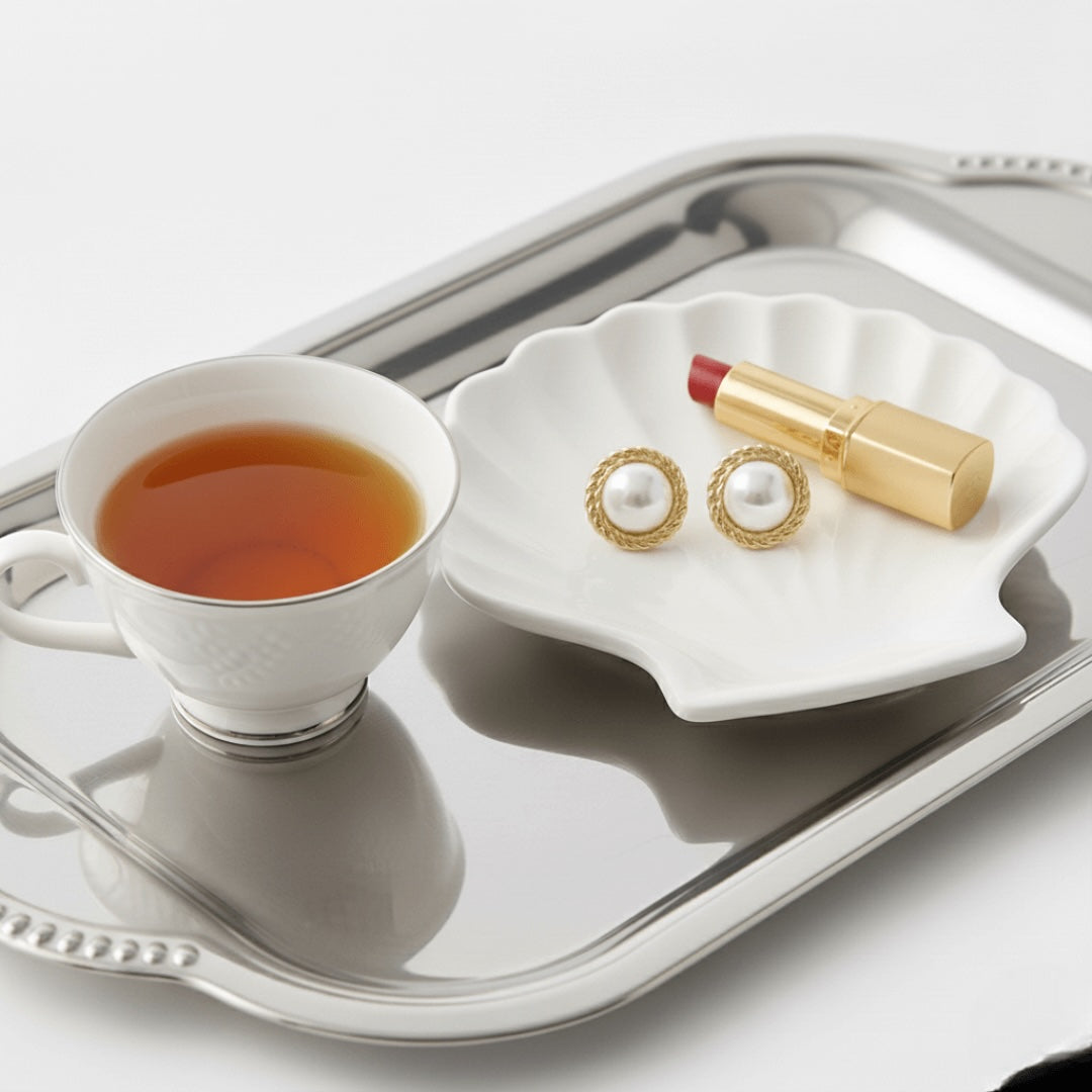 Teacup with tea, Vintaras Elise Pearl Earrings, and lipstick on a silver tray