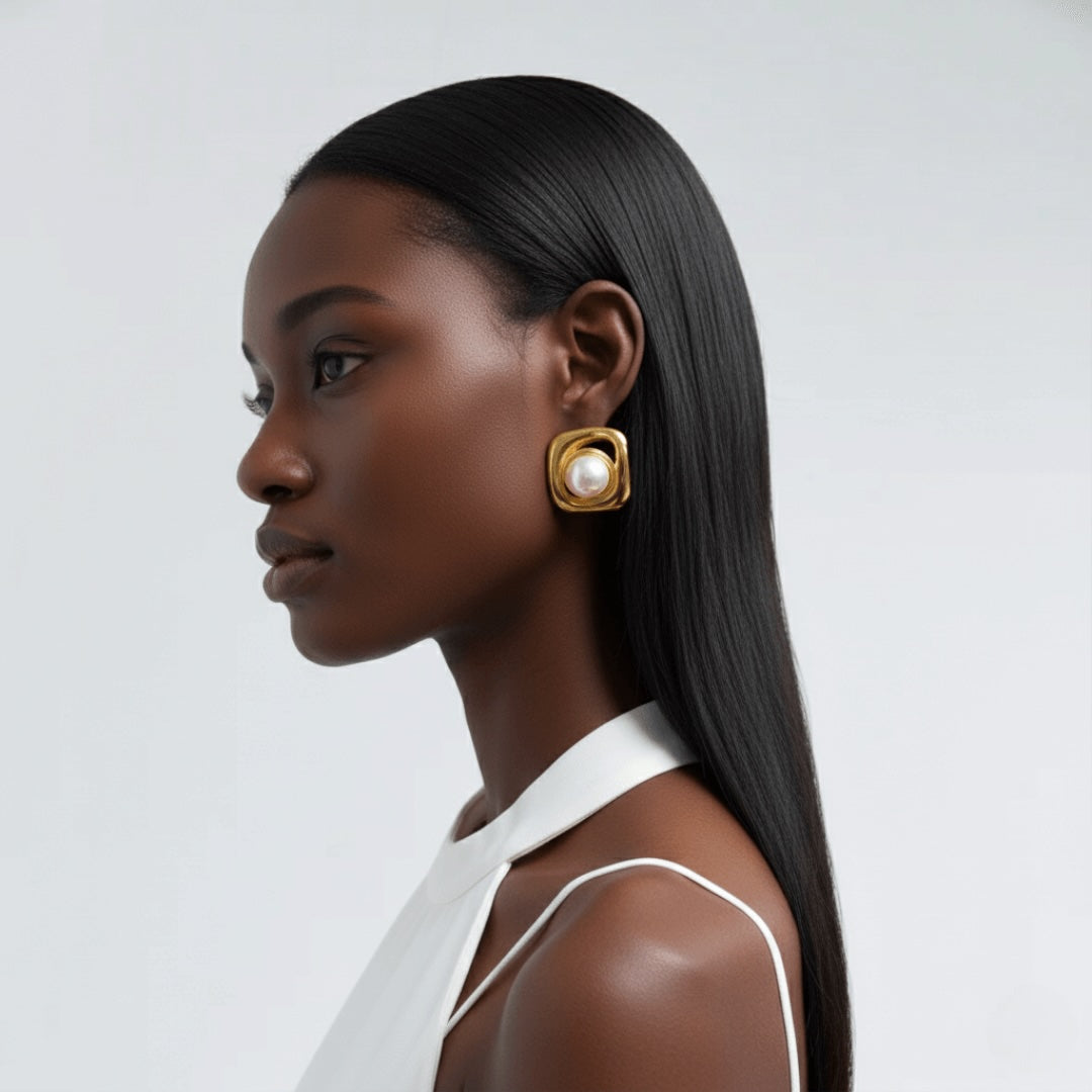 Model wearing gold Vintaras Noa Pearl earring with a white halter neck top on a light gray background