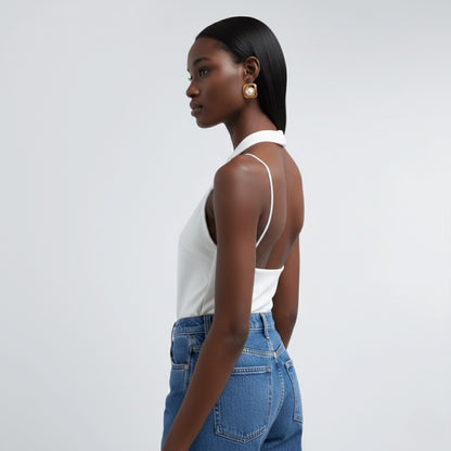 Woman wearing Vintaras Noa Pearl Earrings and a white top and blue jeans against a light gray background