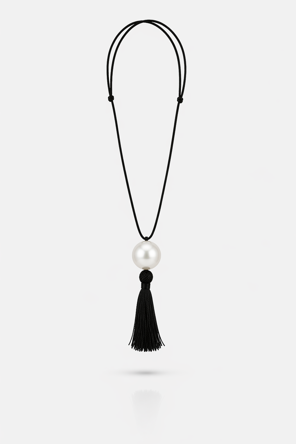 Necklace with a pearl pendant and black tassel on a white background