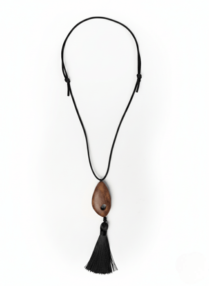 Vintaras Bette Tassel Necklace, a necklace with a wooden pendant and black tassel on a white background.