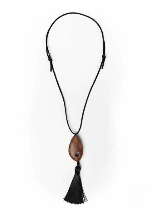 Vintaras Bette Tassel Necklace, a necklace with a wooden pendant and black tassel on a white background.
