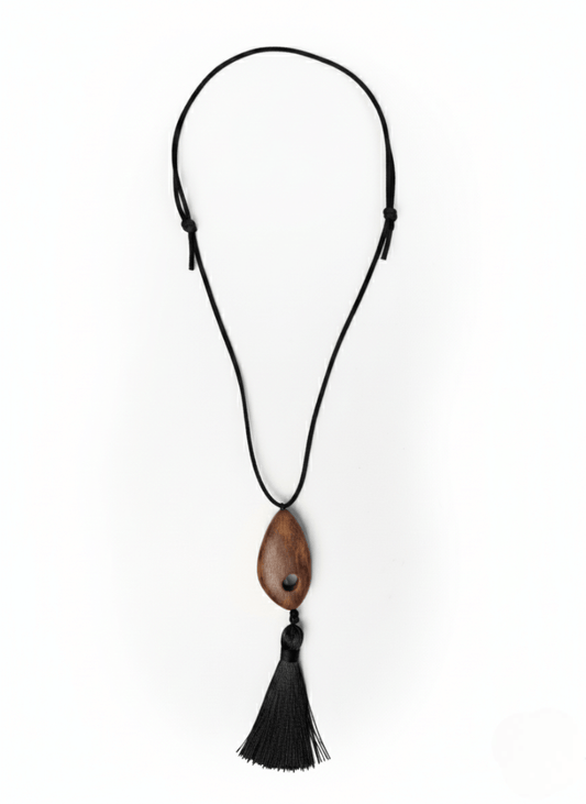 Vintaras Bette Tassel Necklace, a necklace with a wooden pendant and black tassel on a white background.