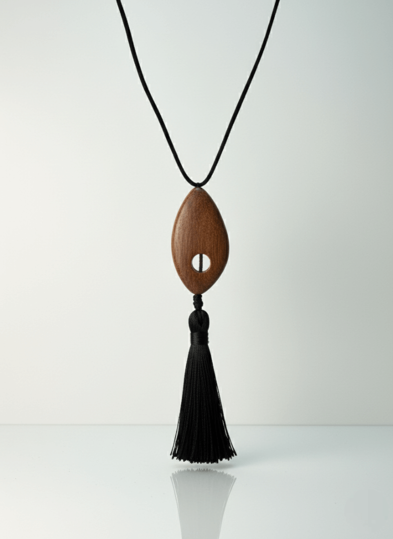 Bette tassel necklace, Wooden pendant necklace with a black tassel on a white background.