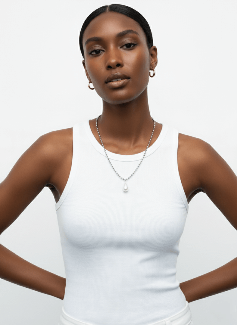 Woman wearing a white tank top and Vintaras Ingrid Necklace Silver with a pearl pendant on a plain background