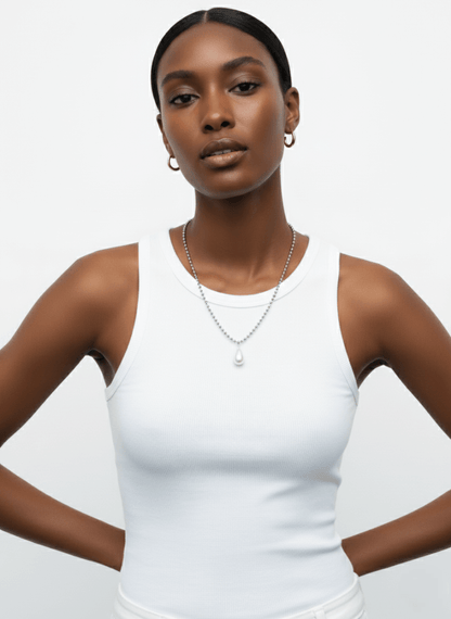 Woman wearing a white tank top and Vintaras Ingrid Necklace Silver with a pearl pendant on a plain background