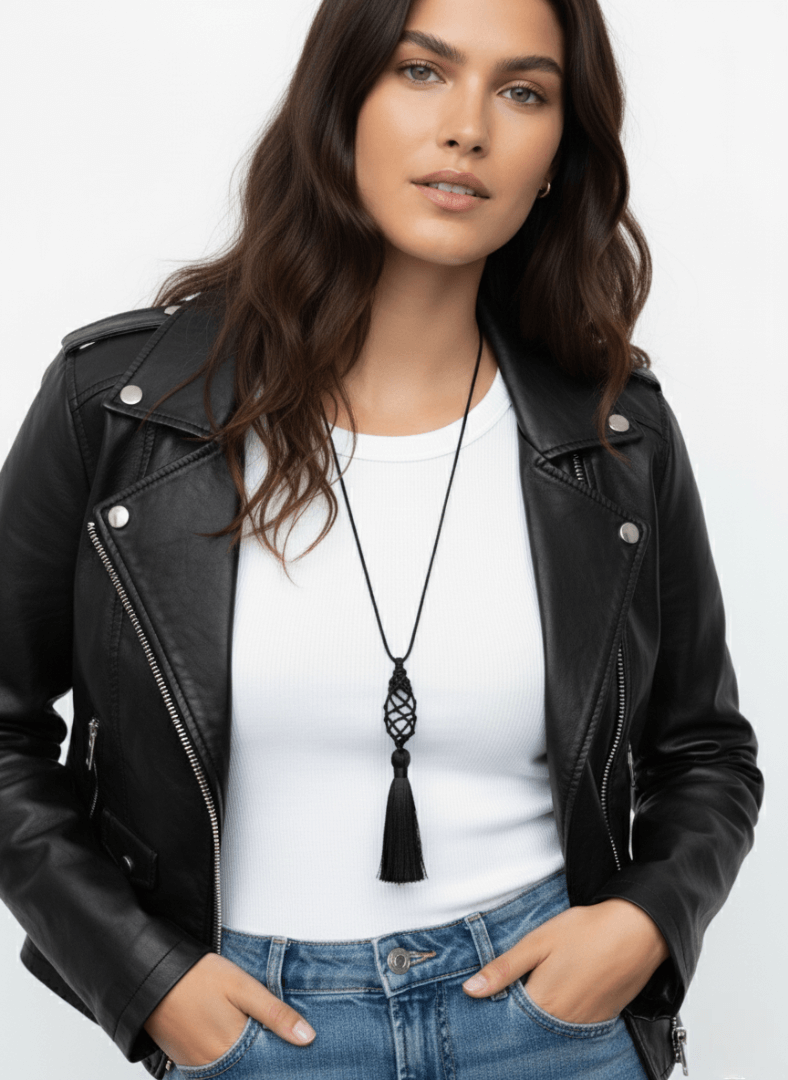 Woman wearing a black leather jacket, white top, and blue jeans with a long black tassel necklace, Vintaras Vivien Tassel Necklace .